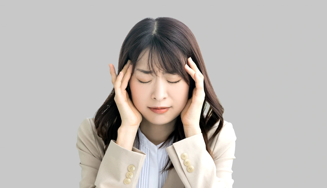 こめかみをおさえている女性